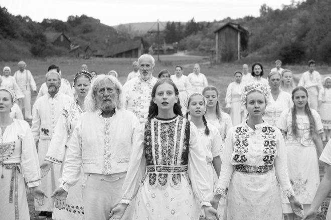 Kadr z filmu "Midsommar". Ludzie w białych strojach z kolorowymi elementami.