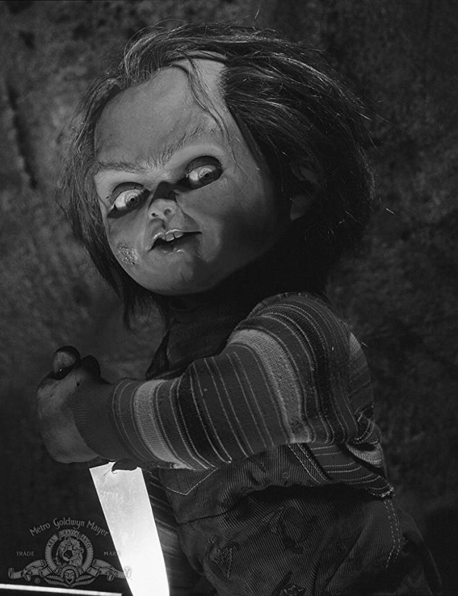 Kadr filmu "Laleczka Chucky". Laleczka trzyma w dłoniach nóż.