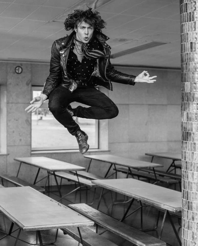 Barns Courtney. Zdjęcie portretowe artysty. Skaczący barns nad stołami.