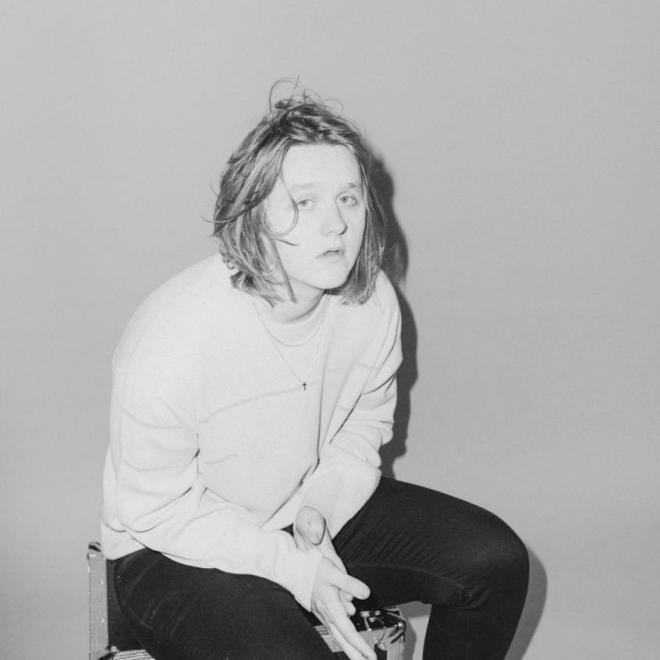 Lewis Capaldi siedzi, patrzy w obiektyw.