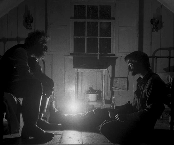 Kadr filmu "Lighthouse". Dwóch mężczyzn. Jeden siedzi na podłodzie, drugi na łóżku.